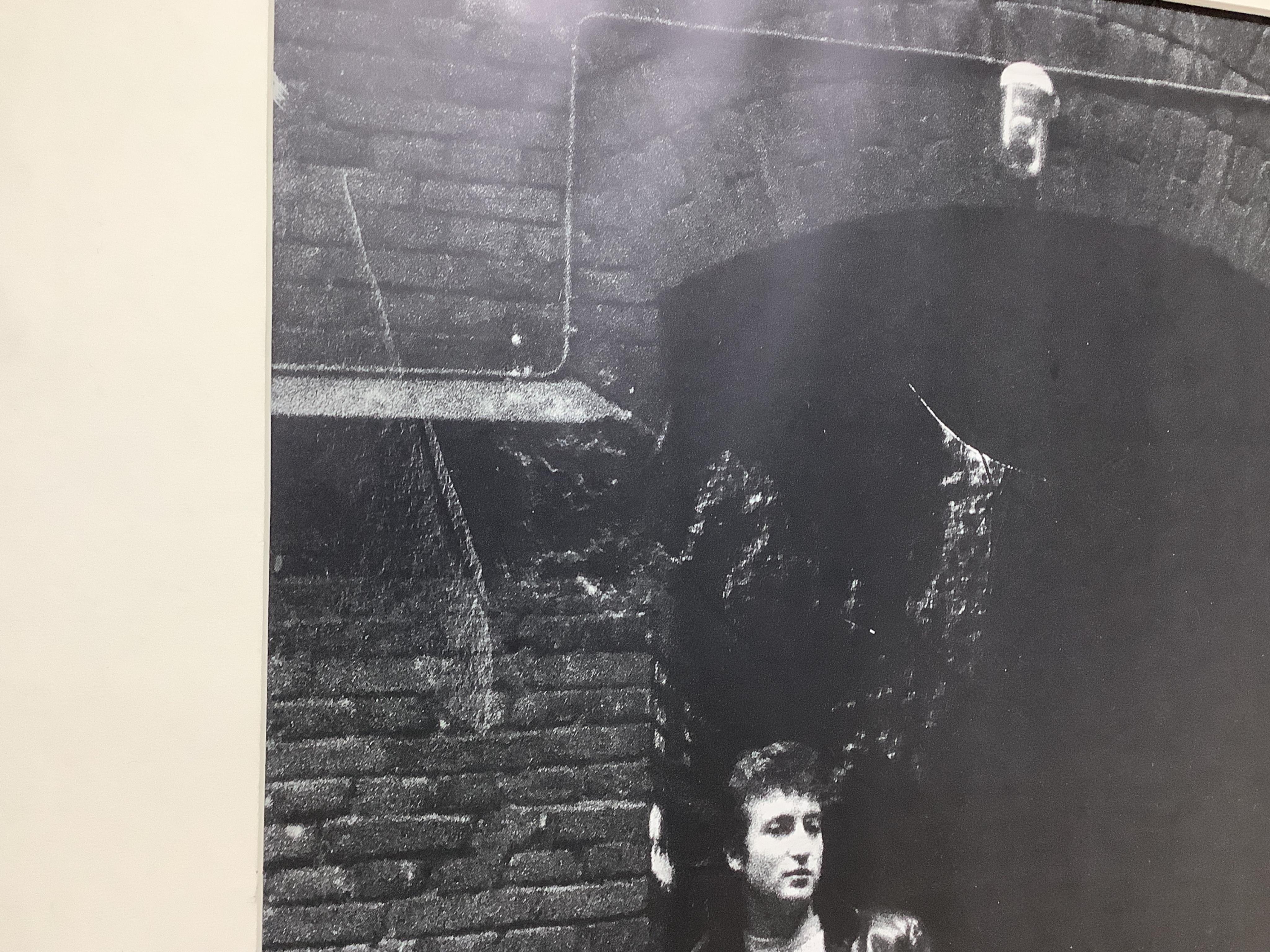 Jurgen Vollmer (German, b.1939), a framed signed limited edition lithograph 83/500 of John Lennon standing in a doorway in Hamburg (glass missing), 79 x 59cm